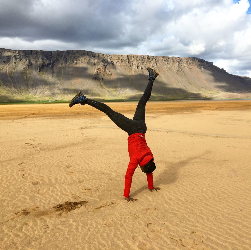 Jumping for joy on a red sand beach in the Westfjords in Iceland