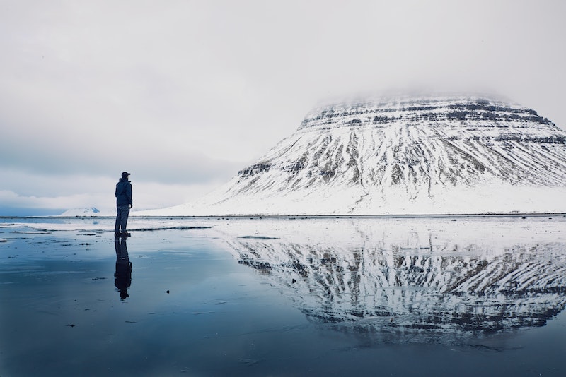 Traveler looking out at on a reflection of a mountain in the water in Iceland